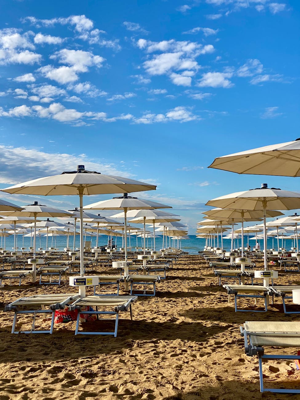 Crowded golden sandy beach at Jesolo Italy with colorful umbrellas, sunbathers, and calm Adriatic Sea waters.